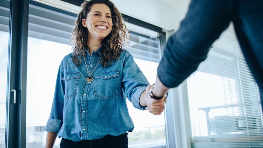 Recruitment manager shakes her hand with male candidate as he gets the job. Businesswoman handshake with a man in office meeting room.
