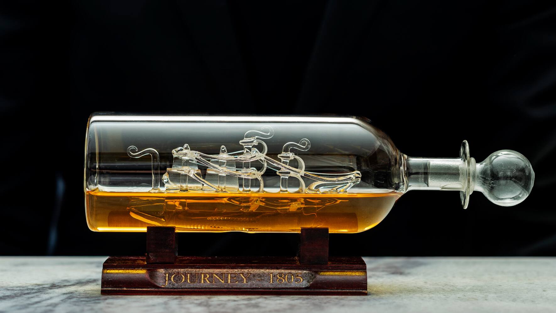 Die Whisky-Flasche mit dem goldenen Getränk und dem gläsernen Segelschiff