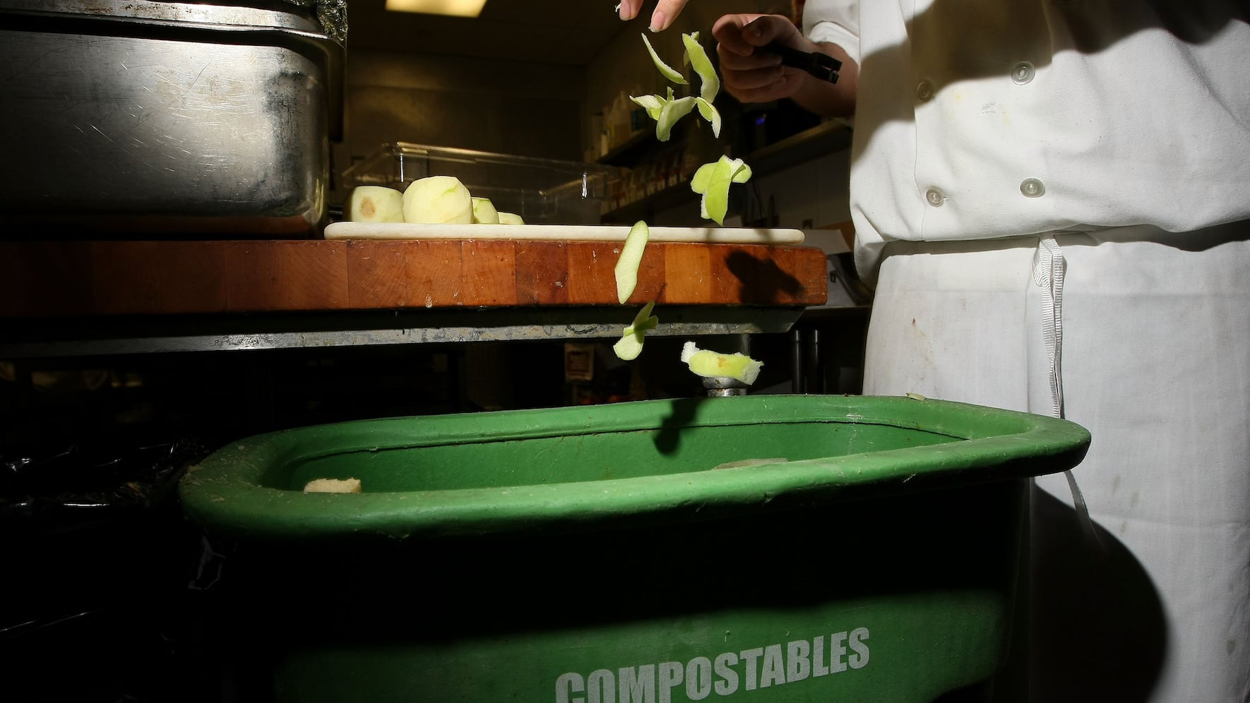 A prep cook at MoMo's restaurant drops apple skins into a food scrap recycling container April 21, 2009 in San Francisco, California.