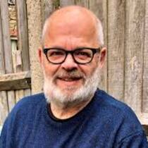 Peter Praschl vor Holzwand porträtiert.