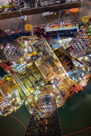 Oil and gas jack-up rig at the yard for maintenance with many vessels in the nighttime, the petroleum rig is applied for producing oil and gas in offshore in the petroleum industry.