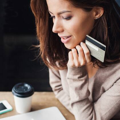 Kreditkarte: wie vergleichen? Frau mit Kreditkarte vor Laptop