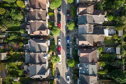 Overhead aerial view of residential homes and road with parked cars