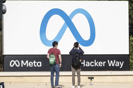 Zwei Personen mit Rücken zur Kamera vor Meta-Schild in den USA.