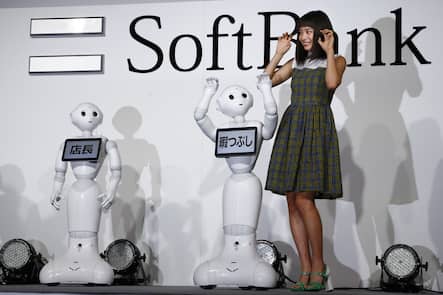 Japanese actress Suzu Hirose and SoftBank's robots Pepper pose for photographers during a media event in Tokyo, Wednesday, Jan. 27, 2016. The monitors read "store manager, left, and "killing time." (AP Photo/Shizuo Kambayashi)