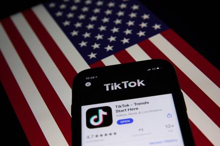 A generic illustration shows the icon of Chinese internet media app TikTok on a phone, and the US flag on a laptop screen.