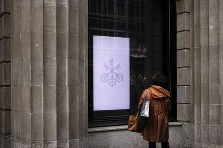 A woman looks at a screen at the entrance of the headquarters of the Swiss bank UBS in Zurich, Switzerland, on Friday, March 24, 2023. (KEYSTONE/Michael Buholzer).