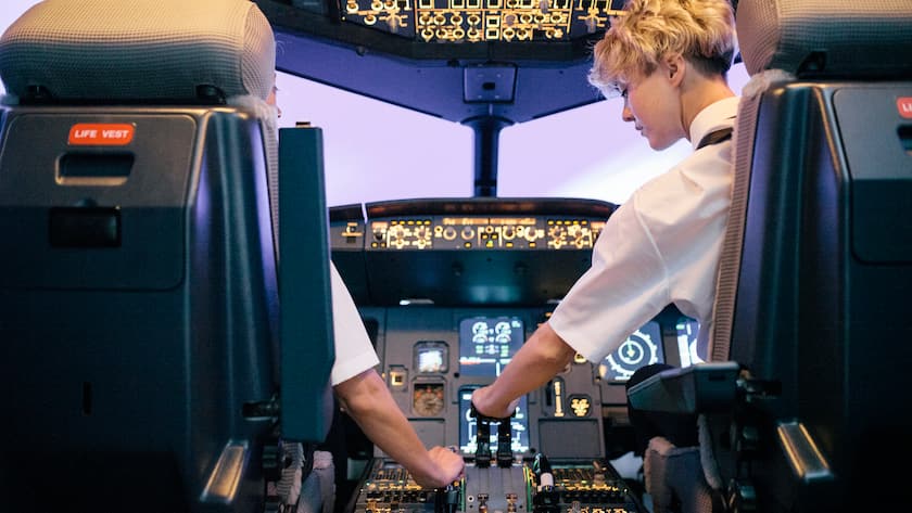 A trainee pilot operating the throttle while on a training session in a flight simulator with an instructor.