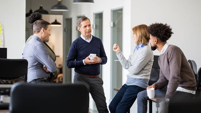 Fünf Personen unterschiedlichen Alters diskutieren miteinander im Büro.