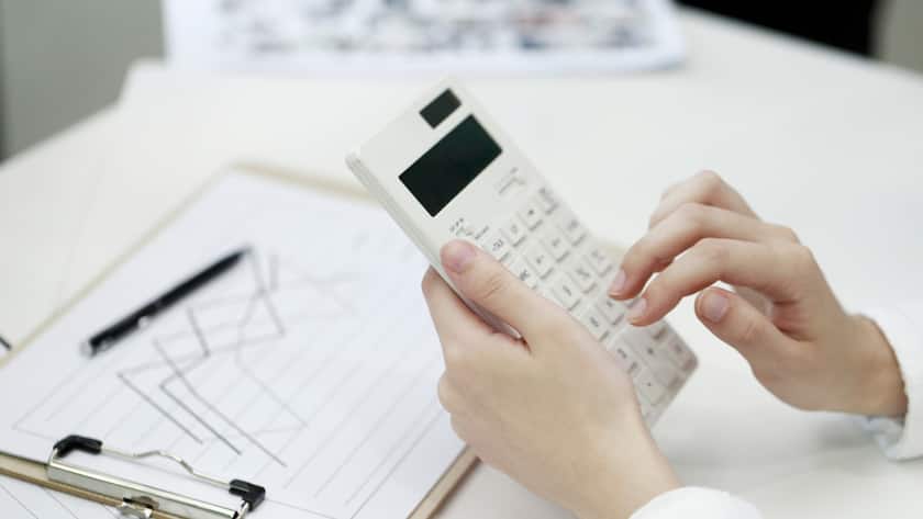 Frau gibt Zahlen im Taschenrechner ein, vor ihr liegen Charts