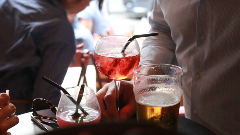 Ein Mann hält ein Glas Sangria mit Eiswürfel, daneben steht ein Bier.