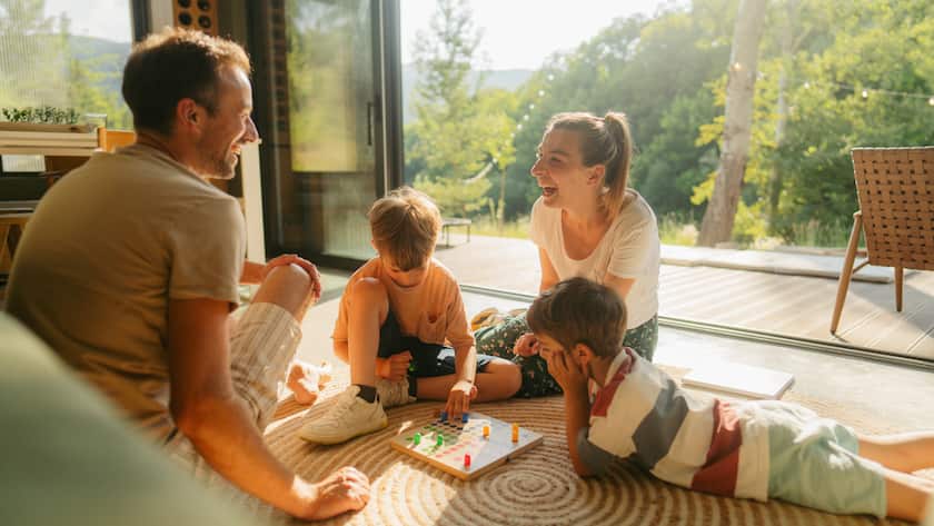 Photo of a young family playing board games together on the floor of their home