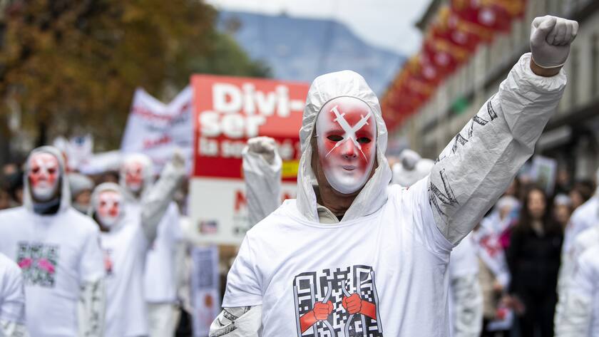 Des personnes manifestent contre la loi Covid-19 avec la presence des Freiheitstrychler lors d'un rassemblement le samedi 13 novembre 2021 a Geneve. (KEYSTONE/Jean-Christophe Bott)