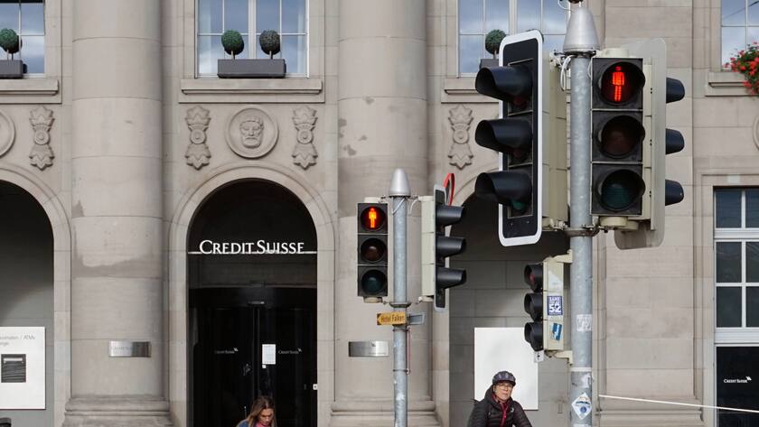 Credit Suisse Logo davor Ampel und einige Personen.