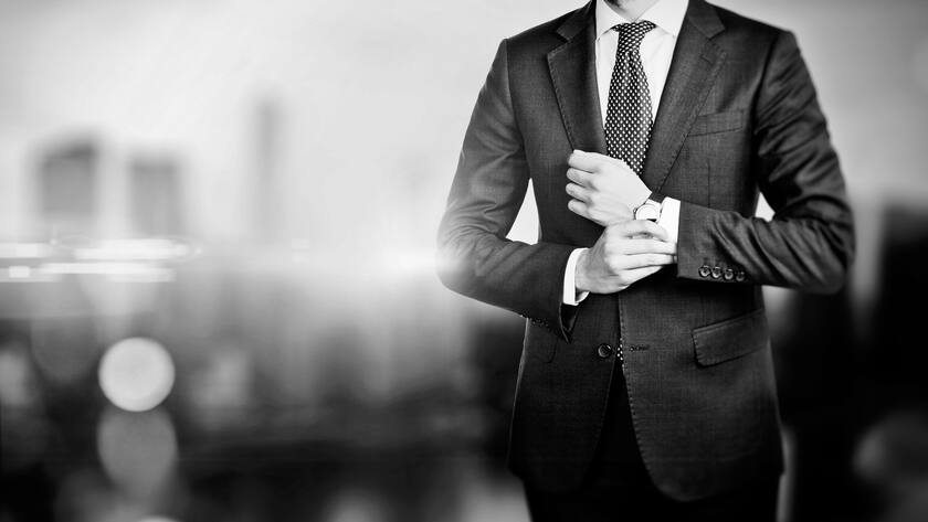 Black and white picture of young businessman touching his watch and the city on the blured background