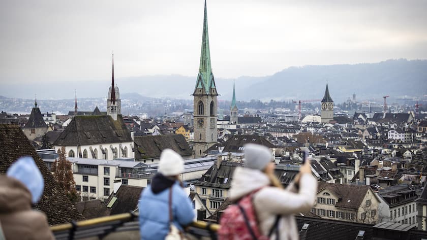 Personen fotografieren mit Smartphones die Stadt Zuerich mit der Predigerkirche, Mitte, dem Grossmuenster, links, dem Fraumuenster, Mitte rechts und der St. Peter Kirche, rechts, von der Polyterrasse der der Eidgenoessischen Technischen Hochschule (ETH) in Zuerich, am 30. November 2024. (KEYSTONE/Michael Buholzer)