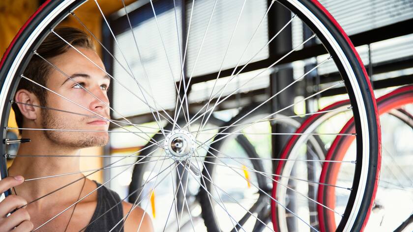 Young man examining spokes on wheel in bicycle shop