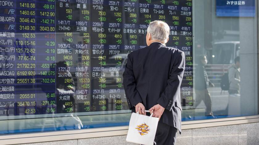 Ein Passant in Tokio beobachtet fallende Aktienkurse.