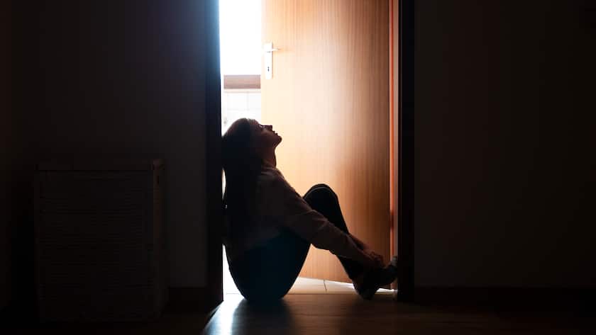 Trauriges Teenager-Mädchen sitzt auf dem Boden vor der Zimmertür