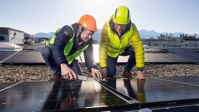 Christophe Bochud von Fromage Gruyère (rechts) und Valentin Bieber von Solstis begutachten die Solaranlage.