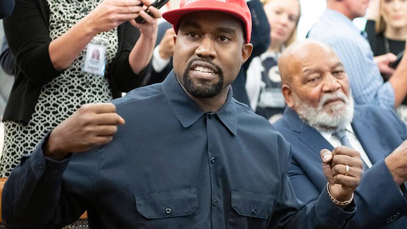 Kanye West mit roter Kappe mit "make America great again" Aufschrift hebt beide Fäuste in die Höhe.