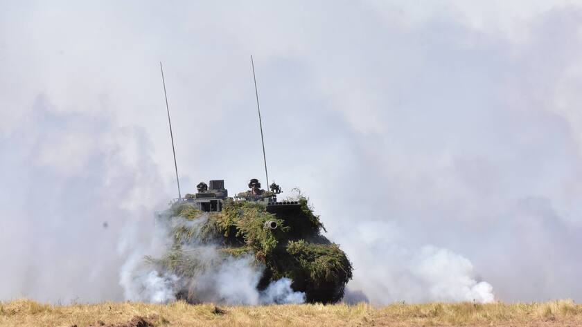 Ein Kampfpanzer vom Typ Leopard 2 A7V der Bundeswehr fährt aus einer Nebelwand, welche er mit seiner Nebelmittelwurfanlage erzeugt hat.