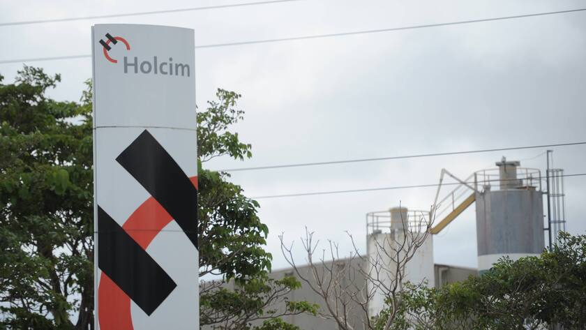 Tafel mit Holcim-Logo vor einer Anlage.