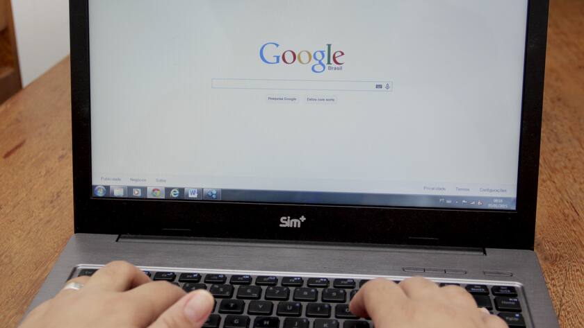 Google-Suchmaschine auf einem Laptop mit zwei Händen auf der Tastatur.