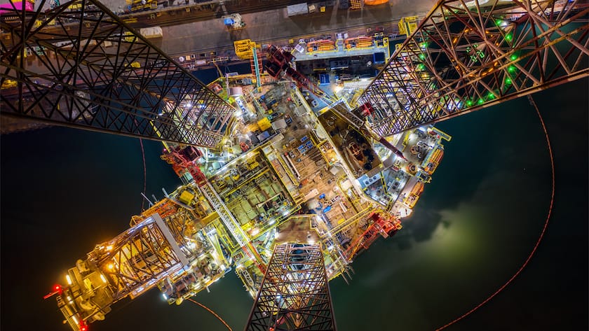 Oil and gas jack-up rig at the yard for maintenance with many vessels in the nighttime, the petroleum rig is applied for producing oil and gas in offshore in the petroleum industry.
