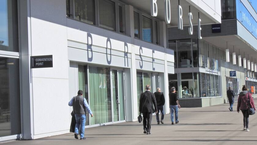 Schweizer Börse mit Logo Schriftzug. Vor dem weissen Gebäude gehen Personen vorbei.