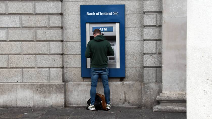 Mann steht mit Rücken zur Kamera an ATM der Bank von Ireland.