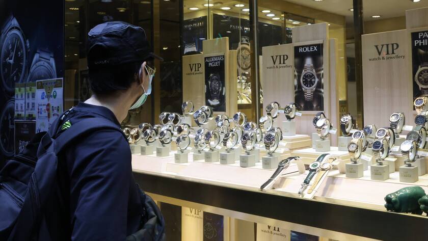 Mann mit Maske und Kappe schaut ins Schaufenster von Rolex-Laden in Hongkong.