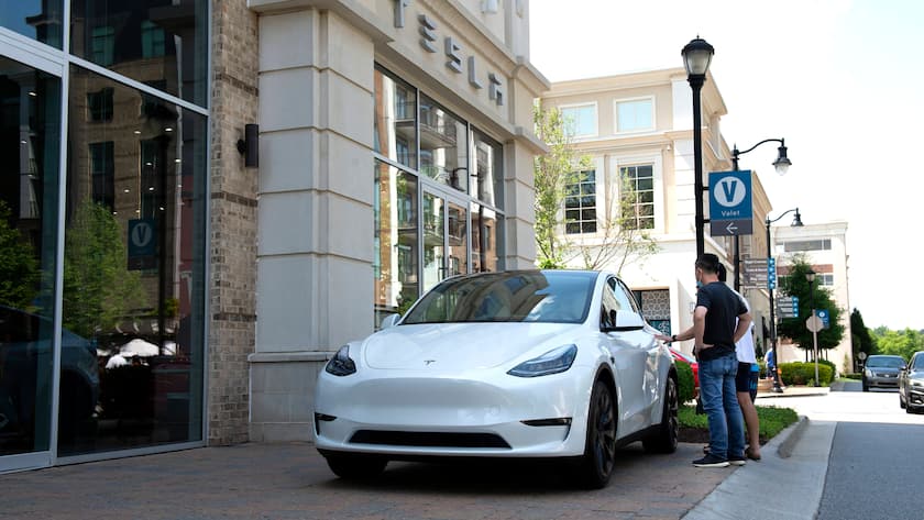 Ein Tesla Model S steht vor einem Tesla Gebäude. Zwei Personen stehen neben dem Auto.