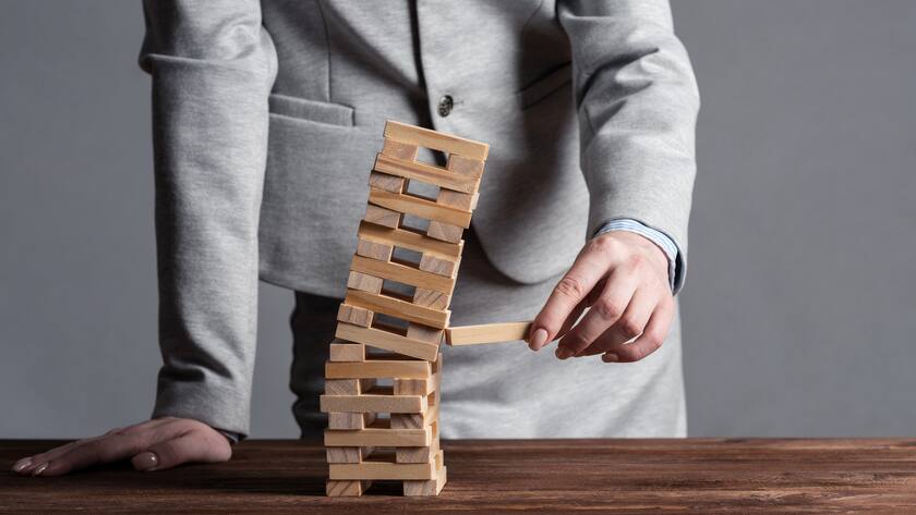 Businesswomen stabilisiert hölzernen Turm in Schieflage - negative Rendite Pensionskasse