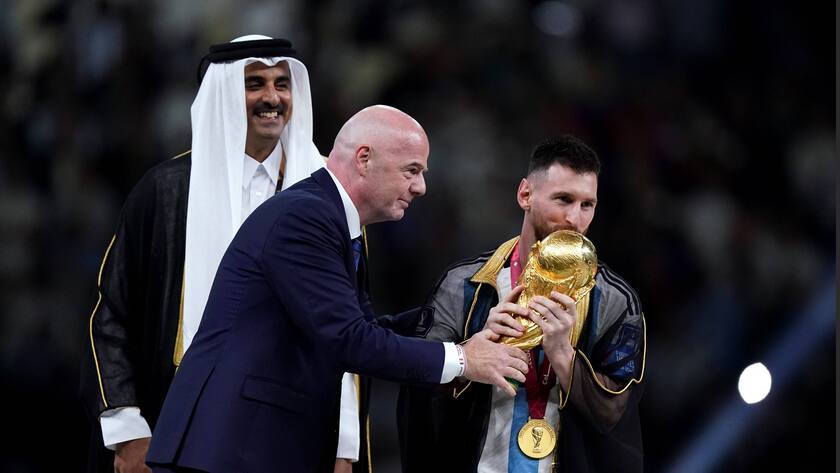 Gianni Infantino übergibt Pokal an Lionel Messi, dieser küsst den Pokal, im Hintergrund steht Schaich Tamim bin Hamad Al Thani.