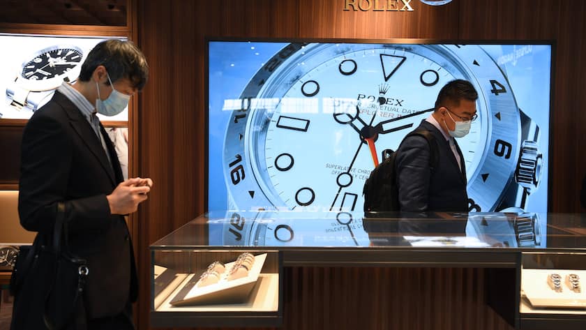 Zwei Männer mit Maske schauen sich Rolex-Luxusuhren an der Uhrenmesse in Shanghai 2021 an.