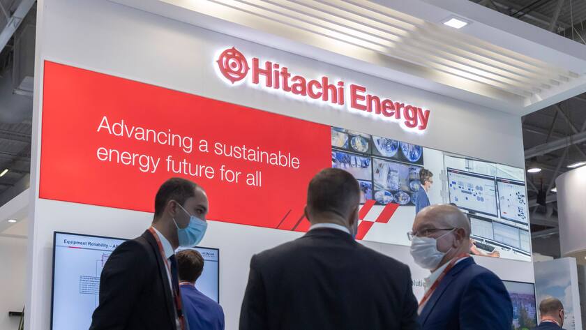 Hitachi Energy Schild mit Personen davor.