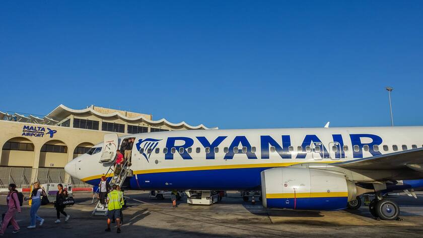 Personen steigen aus Ryanair-Flugzeug aus. Sicherheitspersonal steht davor.