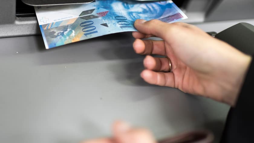 ARCHIV - ZUM SOZIALBERICHT 2016 VOM SCHWEIZER KOMPETENZZENTRUM SOZIALWISSENSCHAFTEN, FORS, STELLEN WIR IHNEN FOLGENDES BILDMATERIAL ZUR VERFUEGUNG - Eine Person entnimmt waehrend des Geldbezuges eine Banknote aus einem Bankautomaten, aufgenommen am 22. September in Zuerich. (KEYSTONE/Christian Beutler)