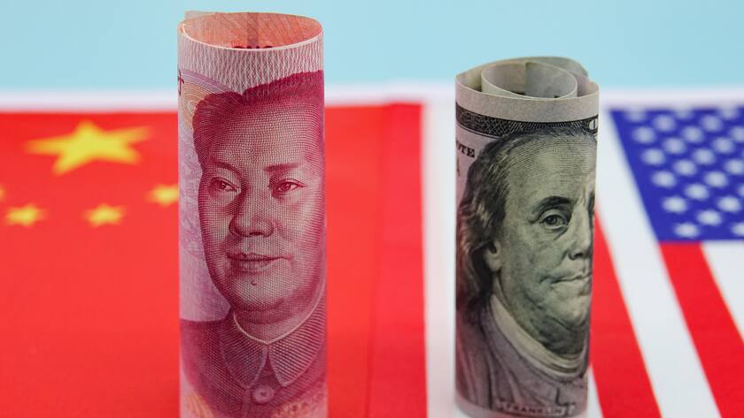 Auf der chinesischen und US-amerikanischen Flagge stehen eingerollt je eine Yuan- und eine Dollarnote.