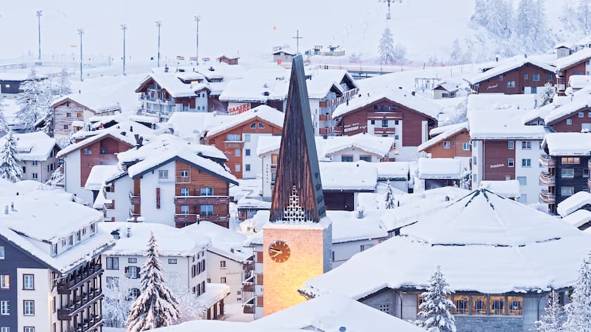 Illuminated bell tower of the church of Saas Fee after a snowfall. Saas Fee, Canton of Valais / Wallis, Switzerland.