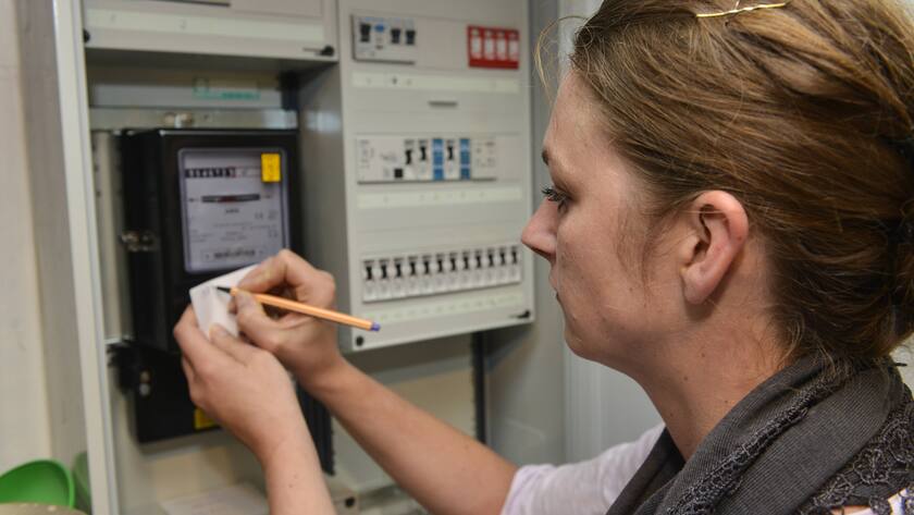 Frau liest Strom ab mit Stift am Zähler.