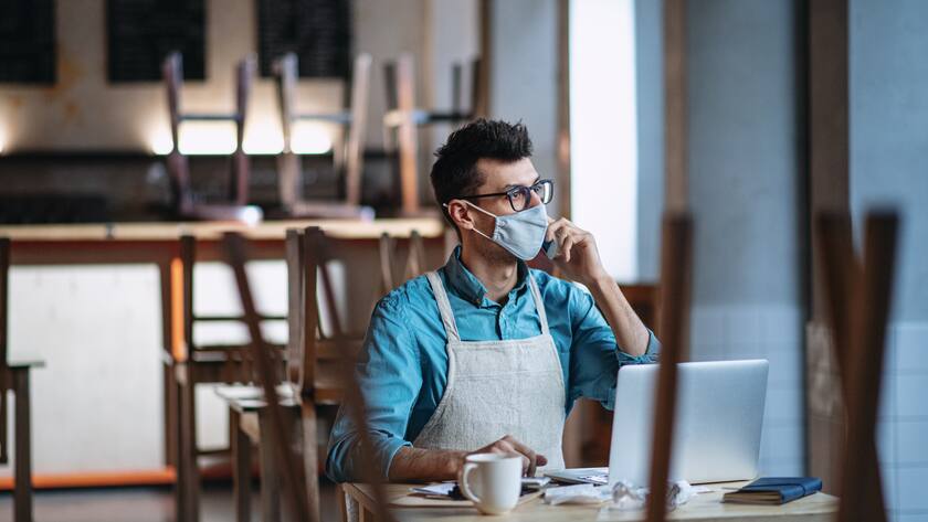 Frustrated owner sitting at table in closed cafe or coffee shop, small business lockdown due to coronavirus.