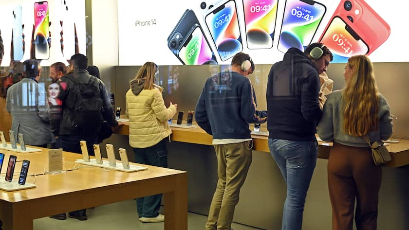 Fünf Personen von hinten in einem Applestore in München schauen sich das iPhone 14 an.