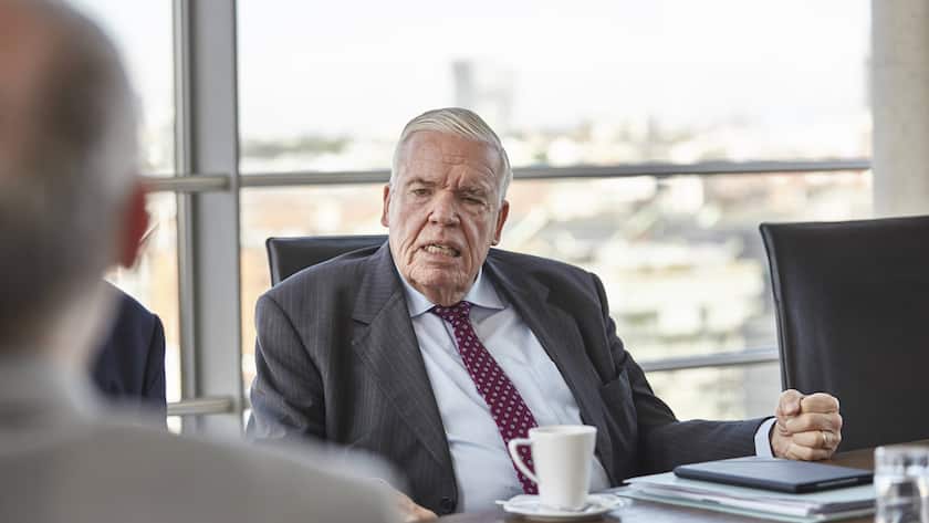 Klaus-Michael Kühne im Anzug mit der Faust auf dem Tisch vor einem Fenster.