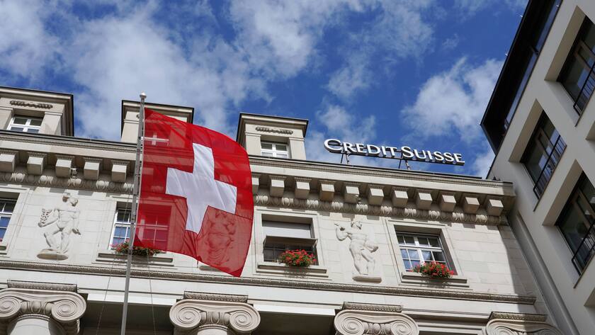 Credit Suisse Gebäude aus Froschperspektive mit einer Schweizer Flagge.