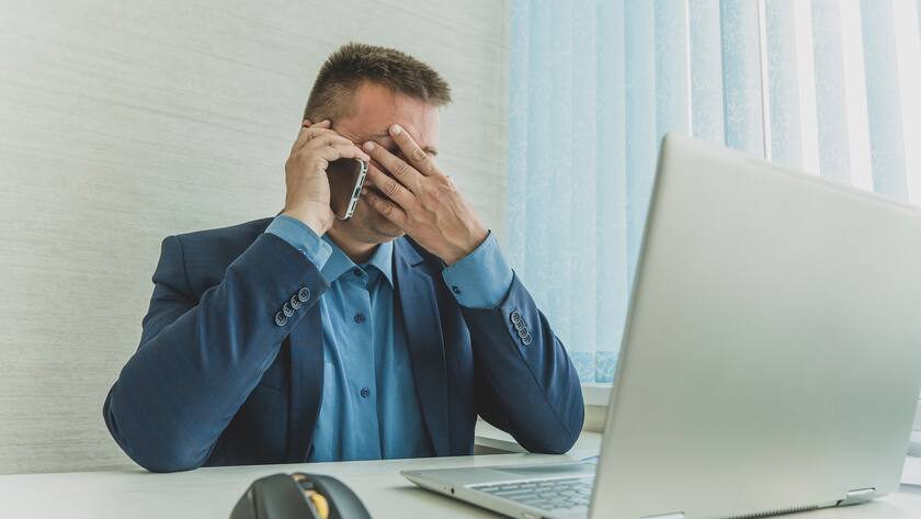 Thoughtful businessman talking on the phone. a tired employee at work in front of a computer monitor. annoying work. A sad businessman. Tired eyesight from working on a laptop.