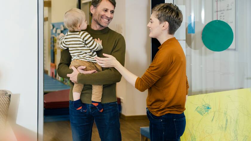 Erzieherin in Kita verabschiedet Vater mit Kind