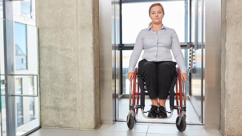 Geschäftsfrau als Rollstuhlfahrerin im Fahrstuhl