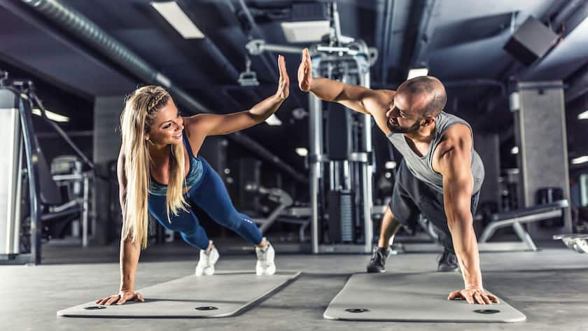 Sport couple doing plank exercise workout in fitness centrum. Man and woman practicing plank in the gym.